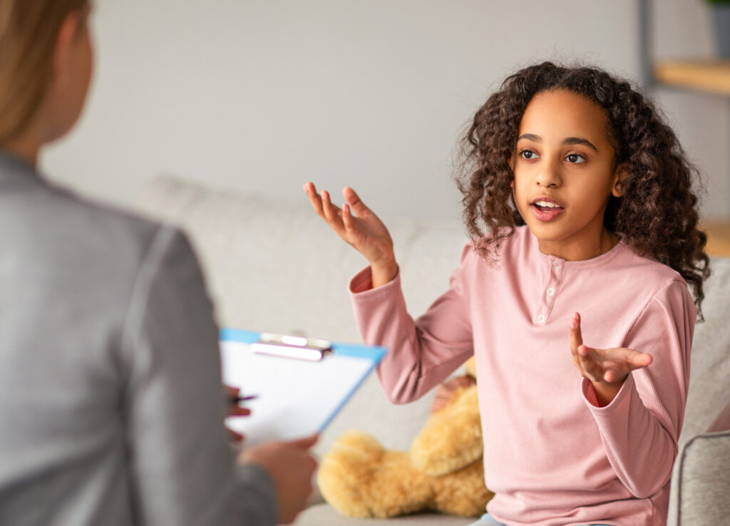 African american teen patient talking to psychologist at her office, expressing emotions.