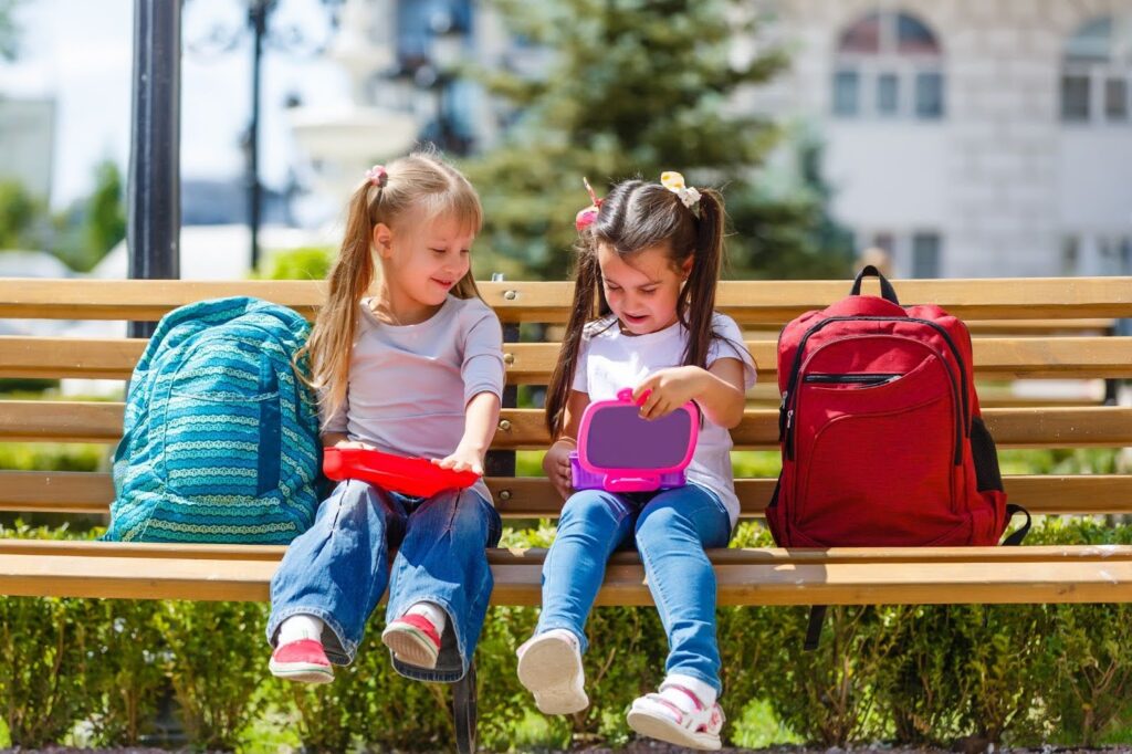 Elementary school kids sitting with packed lunches
