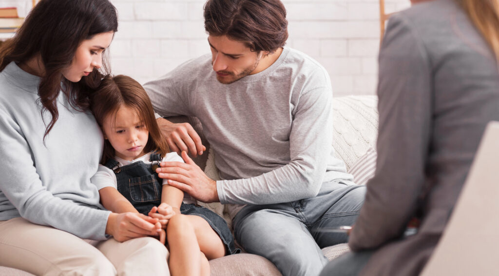 Worried parents comforting their little daughter at psychologist consultation