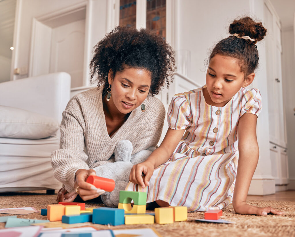 Family, education and building blocks with a daughter learning from her mother on the floor of their living room