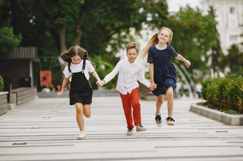 Three children running happily through an urban park